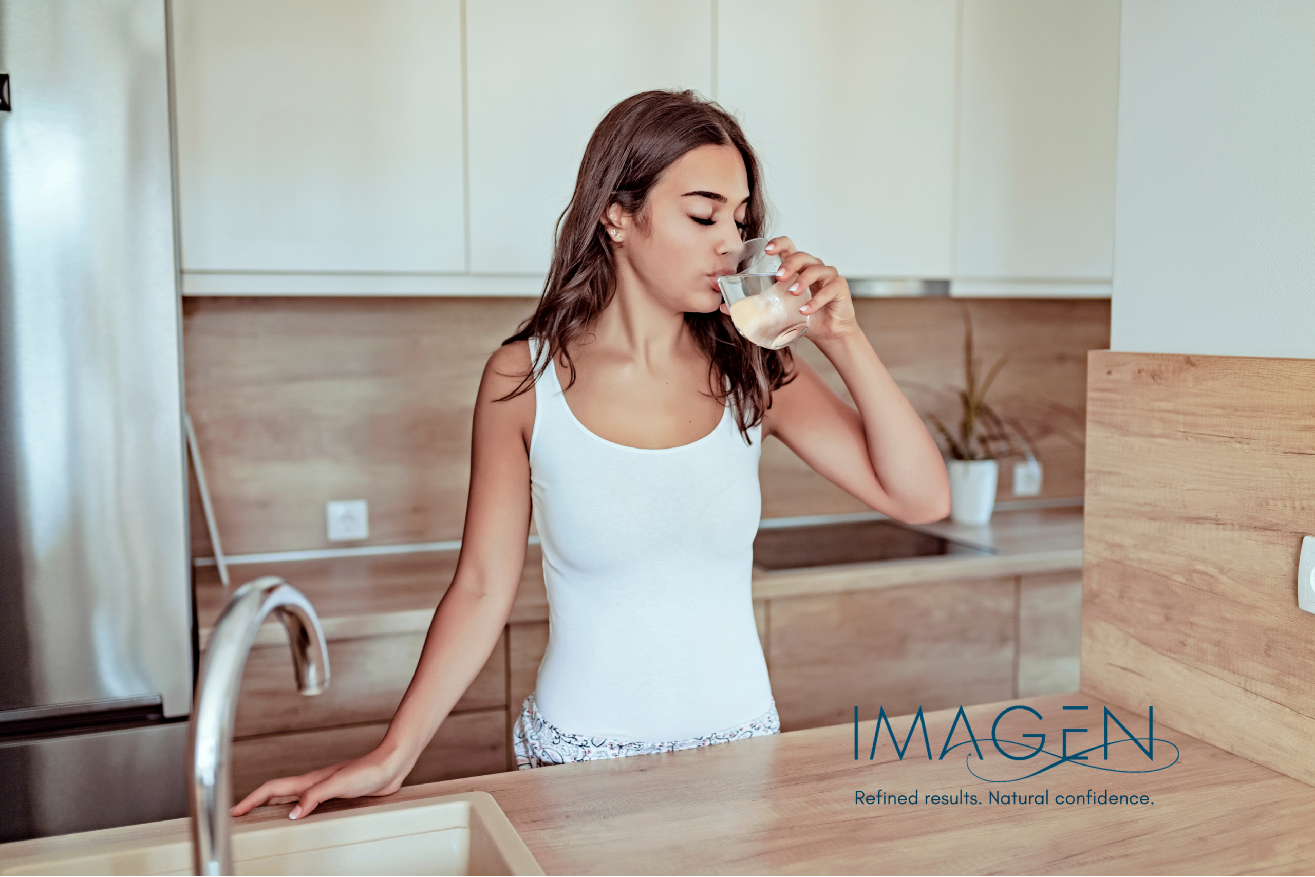 Woman drinking water in a modern kitchen, illustrating healthy hydration habits in Omaha
